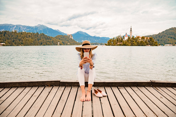 Meisje op een houten pier met smartphone. - Foto, afbeelding