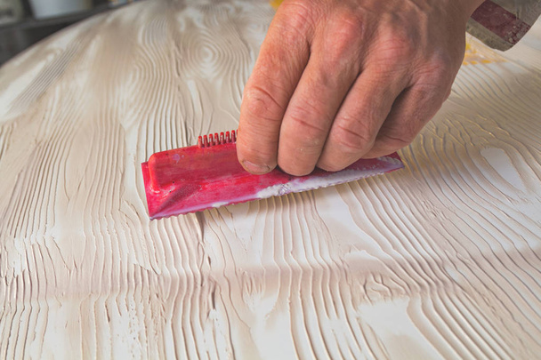 Художник, использующий инструмент для изготовления текстуры искусственного дерева
. - Фото, изображение