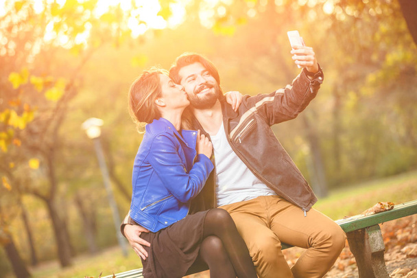 Genç çift sonbahar renkli park'cep telefonu kullanma. - Fotoğraf, Görsel