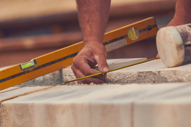Véritable ouvrier de la construction avec ruban de mesure nivellement blocs de béton
. - Photo, image