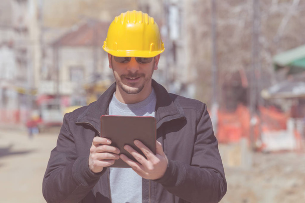 Trabajador de la construcción posando con su tableta al aire libre
. - Foto, imagen