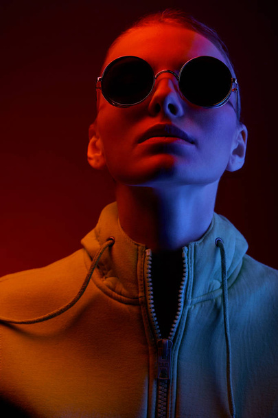 Neon portrait of young woman in round sunglasses. Studio shot  - Photo, Image