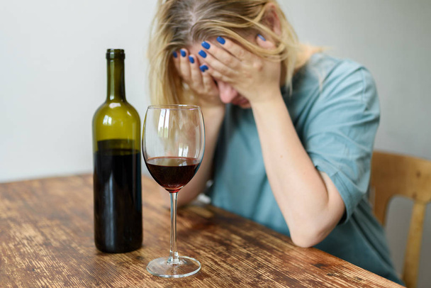  Jeune femme assise à la maison avec un verre de vin rouge. Concept de problèmes sociaux alcooliques
 - Photo, image