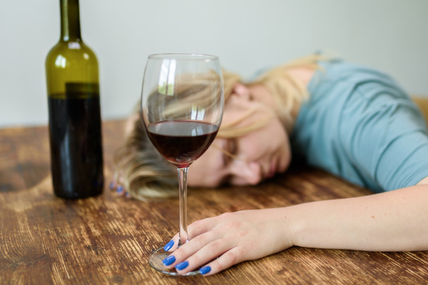  赤ワインのグラスと家で座っている若い女性。アルコールの社会的問題のコンセプト - 写真・画像