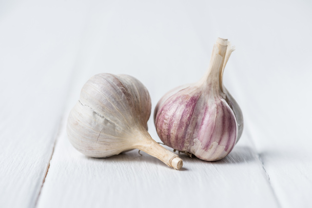 Two garlic heads on white wooden table - Фото, изображение