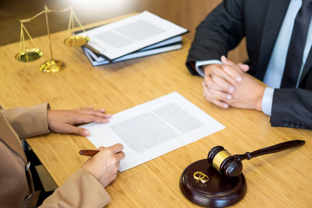couple problems sitting a marriage Golden wedding rings judge gavel deciding on marriage divorce signing divorce documents or premarital agreement provide legal advice of lawyer and consoling to his clients - Photo, Image