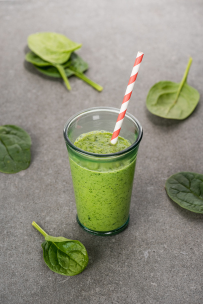 Spinach leaves and green organic smoothie in glass with straw  - Foto, Bild