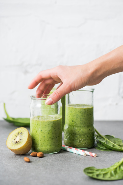 Female hand holding glass with green smoothie - Photo, Image