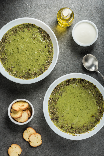 pohled shora ze dvou misek s zelená Špenátová polévka, kysaná smetana, olej a krutony - Fotografie, Obrázek