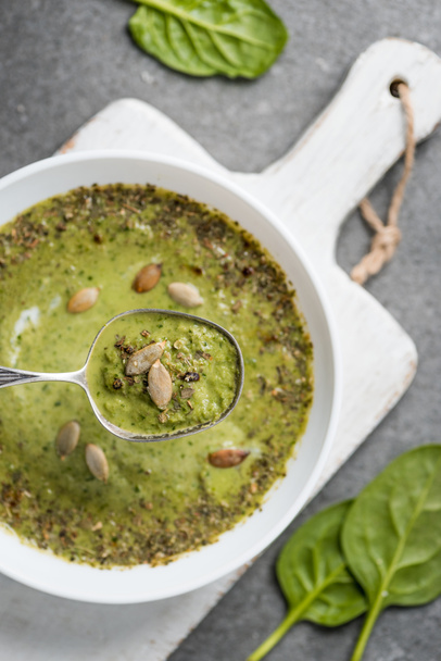 Close up of silver spoon with green vegetable creamy soup in bowl - Fotoğraf, Görsel