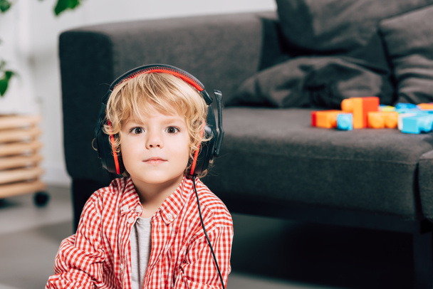 close up portrait of little boy listening music in headphones and looking at camera - Фото, зображення