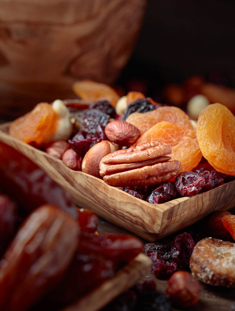 Erilaisia kuivattuja hedelmiä ja pähkinöitä vanha puinen pöytä. Valikoiva painopiste
. - Valokuva, kuva