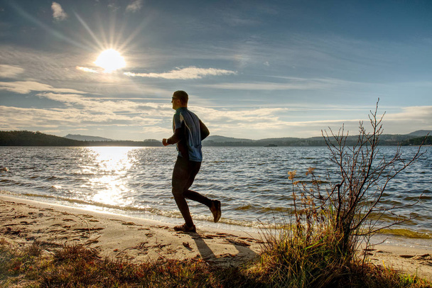 Hombre Activo corriendo en el lago. Viaje aventura estilo de vida saludable concepto vacaciones, persona atlética
  - Foto, Imagen