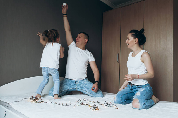 family, father mother and girl are playing on the bed - Foto, imagen