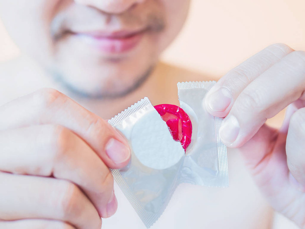 Man is tearing red condom package safe sex concept - Foto, Imagem