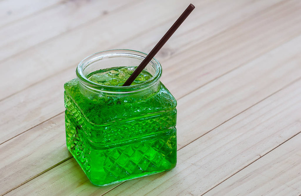 Cold green soda in a big glass over wooden background - 写真・画像