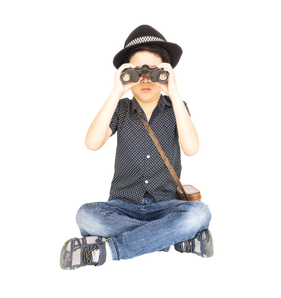 7 years old Asian traveler boy is sitting and using binoculars isolated on white background - 写真・画像