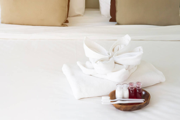 Hotel towel set with toothbrush and toothpaste on white bed - Fotó, kép