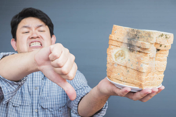 Man showing dislike to old fungi decay bread - Фото, зображення
