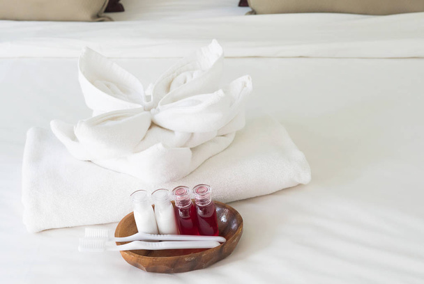 Hotel towel set with toothbrush and toothpaste on white bed - Foto, Bild