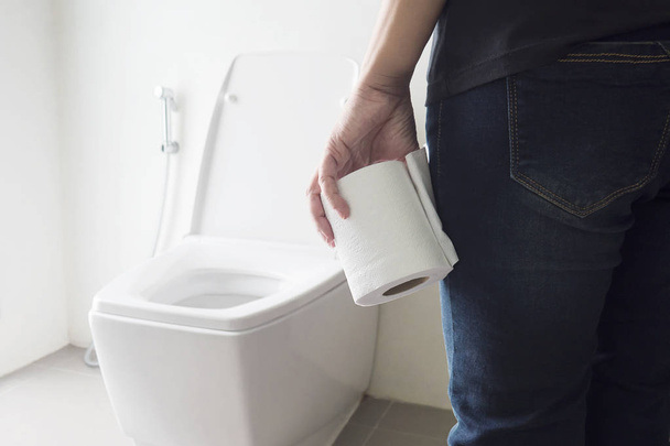 Lady holding tissue near a toilet bowl - Photo, image