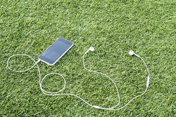 Mobile phone with head phone on green artificial grass - Zdjęcie, obraz