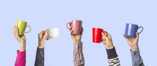 Many different hands holding multi colored cups of coffee on a blue background. Female and male hands. Concept of a friendly team, a coffee break, meeting friends, morning in the team. Banner. - Valokuva, kuva