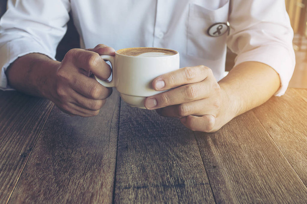 cropped image of man holding vintage coffee with Latte art decoration - Photo, image