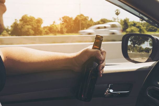 Man holding beer bottle while driving a car - Fotoğraf, Görsel