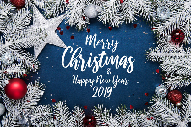 Merry Christmas and Happy Holidays greeting card, frame, banner. New Year. Noel. Christmas ornaments and fir tree on blue background top view. Winter holiday theme. Flat lay. - Photo, image