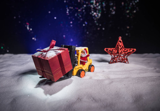 Miniatyyri lahjapakkaus haarukkatrukin koneella lumessa, määrätietoinen kuva joululomalle ja onnellista uudenvuoden lahjakonseptia varten. Valikoiva painopiste
 - Valokuva, kuva