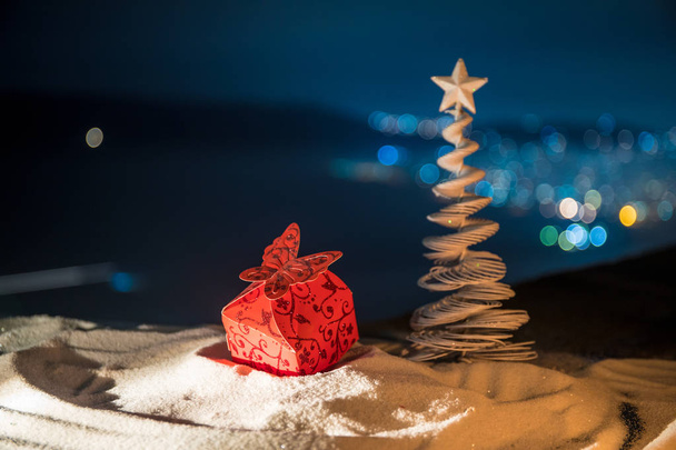 Christmas decorations. Fir tree standing on snow with beautiful holiday decorated background and traditional holiday attributes. Selective focus. Empty space for your text - Photo, Image