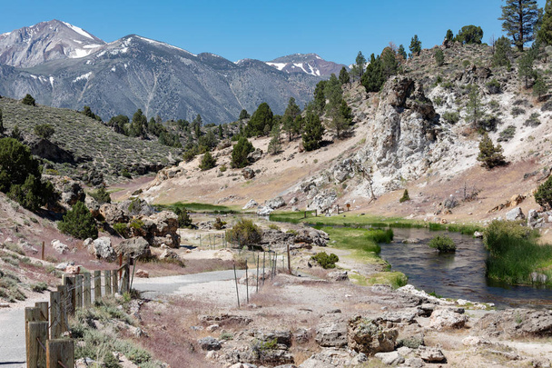 Hot Creek has dozens of natural hot springs bubbling up within the rocky walls of a river gorge and in the shadows of towering Eastern Sierra mountain peaks. Itis a breathtaking place where boiling, bubbling water rich in dissolved minerals emerge - Photo, Image
