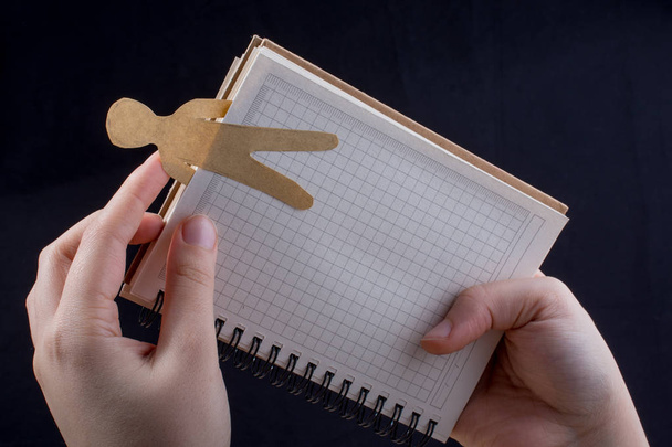 Ανδρικό σχήμα κομμένο από χαρτί σε notebbok στο χέρι - Φωτογραφία, εικόνα