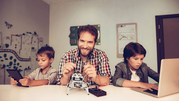 Bearded Father and Son Constructing Robot at Home. Young Boy in Shirt. Indoor Joy. Modern Hobby Concept. Modern Technology. Robot Engineering Concept. Bearded Young Man. Innovation for Fun. - Foto, Bild