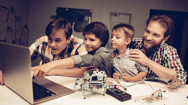 Bearded Father and Sons Constructing Robot at Home. Young Boy in Shirt. Indoor Joy. Modern Hobby Concept. Modern Technology. Robot Engineering Concept. Bearded Young Man. Innovation for Fun. - Photo, image