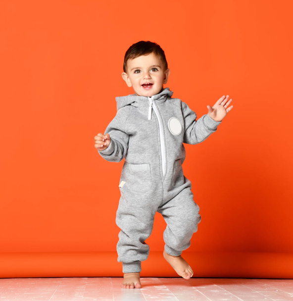 Infant child baby boy kid toddler in light gray body cloth make first steps - Φωτογραφία, εικόνα