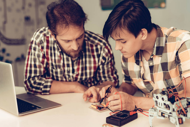 Bearded Father and Son Constructing Robot at Home. Young Boy in Shirt. Indoor Joy. Modern Hobby Concept. Modern Technology. Robot Engineering Concept. Bearded Young Man. Innovation for Fun. - Foto, Imagen