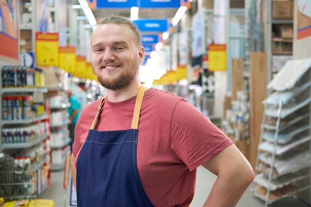 Χαμογελώντας γενειοφόρος πωλητής στο κατάστημα σούπερ κατασκευή - Φωτογραφία, εικόνα