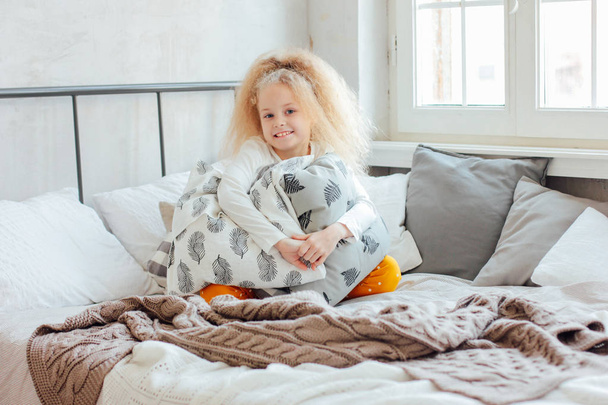 Маленькая красивая кудрявая блондинка проснулась и улыбнулась, уютное утро
 - Фото, изображение