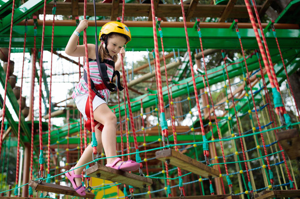 Orman macera parkında bir çocuk. Çocuklar yüksek ip izlerine tırmanıyor. Çeviklik ve çocuklar için açık hava eğlence merkezine tırmanma. Küçük kız dışarıda oynuyor. Okul bahçesinde iple oyun oynanır.. - Fotoğraf, Görsel