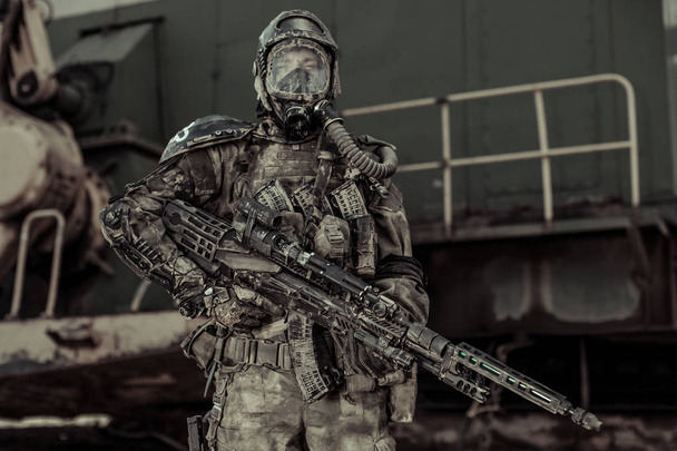 armed man in chemical protection standing near iron structure, Apocalypse concept  - Foto, afbeelding