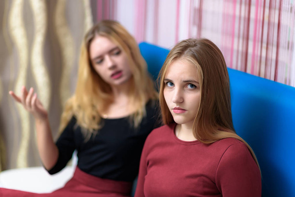 Aile sorunları kavramı iki güzel genç hoşnutsuz lezbiyen kız kanepede oturan bir odada konuşuyor. Kamera önünde doğru ve mutsuz bak. - Fotoğraf, Görsel