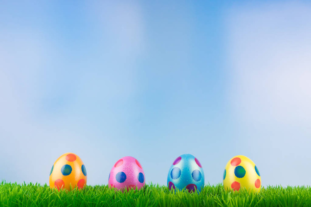 Colorido pontilhado ovos de Páscoa na grama, fundo céu azul e espaço de cópia
 - Foto, Imagem