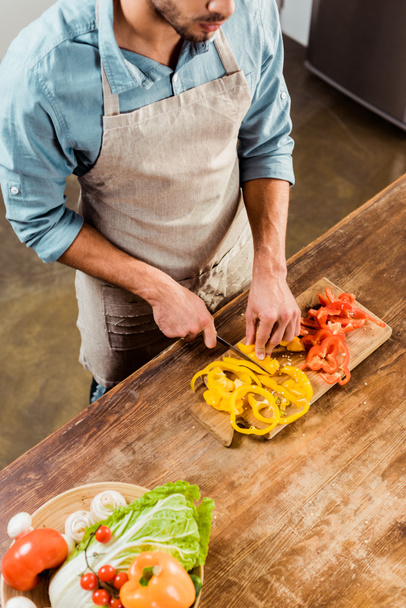 high angle view of man in apron cutting vegetables in kitchen - Foto, Imagem