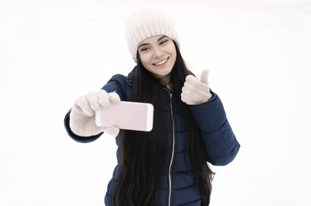 dívka s chytrým telefonem volá kamaráda v parku na zimní den, videohovor, zimní mrazivý den - Fotografie, Obrázek