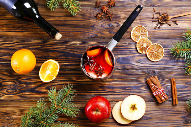 Christmas composition with mulled wine with its ingredients & spices on wooden textured table. Traditional drink on winter holiday season. Copy space, close up, top view, background. - Fotoğraf, Görsel