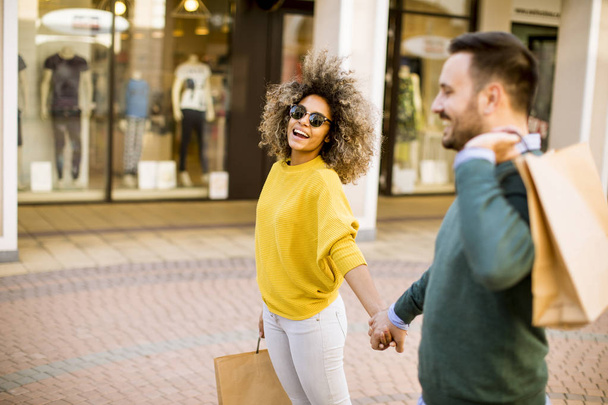Preciosa joven pareja multiétnica con bolsas en las compras
 - Foto, imagen