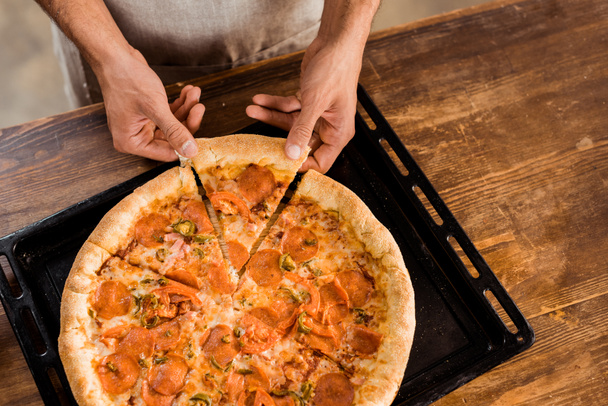 Erschossener Mann hält Pizzascheibe auf Backblech - Foto, Bild