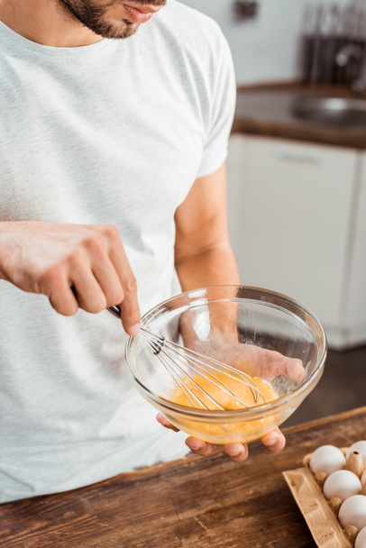oříznutý snímek mladého muže, šlehání omeleta v misce na ranní - Fotografie, Obrázek